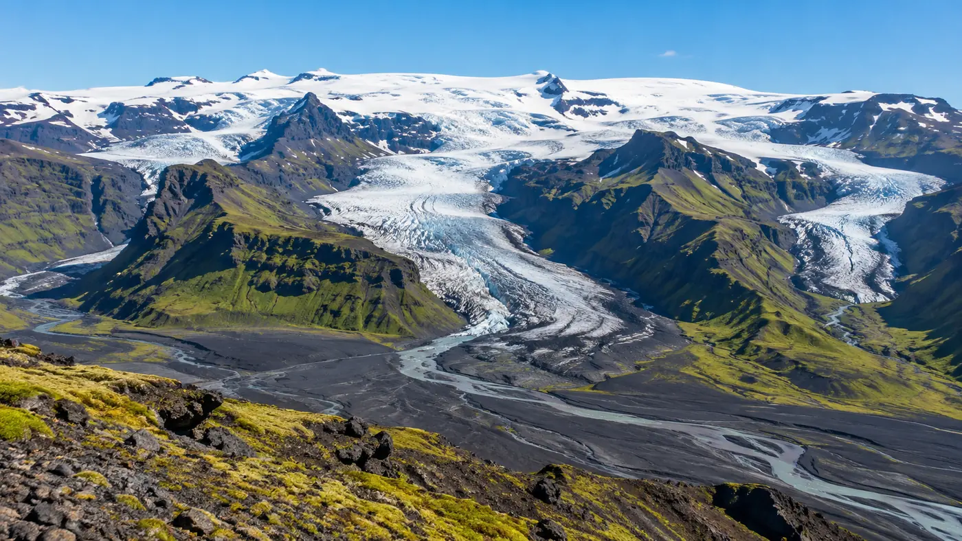 Aerial view of an Icelandic ice cap with outlet glaciers spilling down between dark mountains