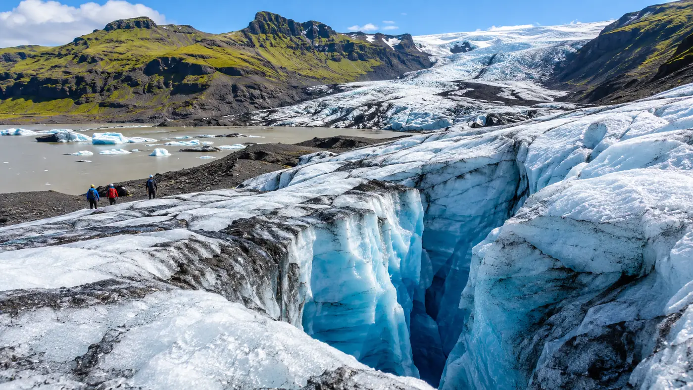 Looking down into a deep, narrow crevasse with walls of bright blue ice